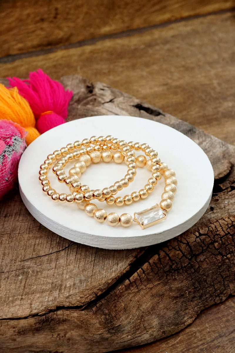 Gold tone multi size ball beaded bracelet stack with a Crystal